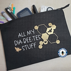 May include: Black zippered pouch with the text "ALL MY DIA-DEE-TES STUFF" in white lettering. A gold honeycomb design with bees is on the pouch. The text "MAJESTIC BEE CRAFTS" is in a circle with a bee in the center.