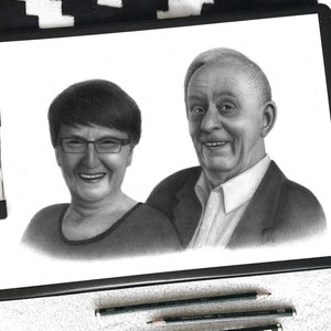 May include: A black and white pencil drawing of an older couple. The woman is smiling and wearing glasses. The man is smiling and has a kind expression. The drawing is on a white background.