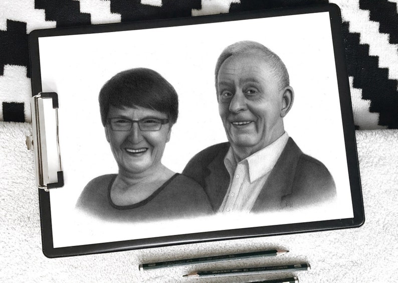 May include: A black and white pencil drawing of an older couple. The woman is smiling and wearing glasses. The man is smiling and has a kind expression. The drawing is on a white background.