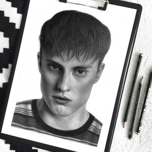 May include: A black and white pencil drawing of a person's face. The person has short, dark hair and is wearing a striped shirt.