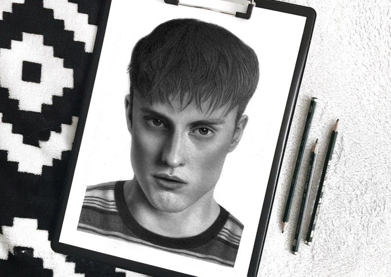 May include: A black and white pencil drawing of a person's face. The person has short, dark hair and is wearing a striped shirt.