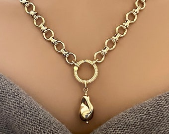 May include: Gold-toned necklace featuring a chunky chain design. The necklace has a circular pendant with a gemstone border, and a teardrop-shaped charm. The jewelry is displayed against a neutral background.
