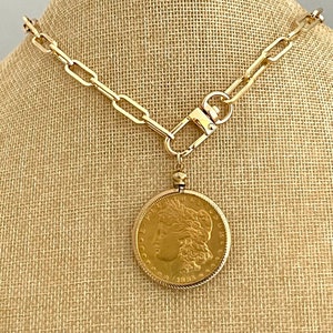May include: A gold chain necklace with a gold coin pendant. The coin features a profile of a woman's face.