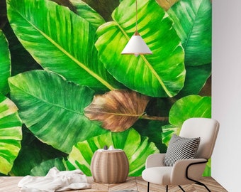 May include: A watercolor painting of large green leaves with a white pendant light hanging above. A white chair with a black and white striped pillow sits in front of the painting. A small wooden stool sits in front of the chair.