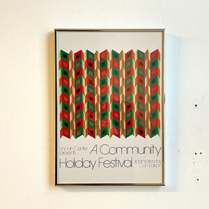 May include: Framed poster with a geometric design in red, green, and black. The poster reads "A Community Holiday Festival" with the Lincoln Center and Con Edison logos. The artwork is in a silver frame.