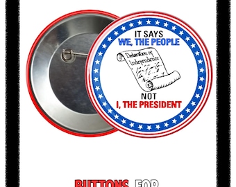 May include: A red and white button with the text "IT SAYS WE, THE PEOPLE" and "NOT I, THE PRESIDENT". The button features a scroll illustration of the Declaration of Independence and is surrounded by a blue ring with white stars. The words "BUTTONS FOR DEMOCRACY" are at the bottom.