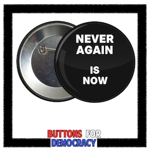 May include: A black button with the text "NEVER AGAIN IS NOW" in white. The button is round and has a pin back. The words "BUTTONS FOR DEMOCRACY" are at the bottom in red and blue.
