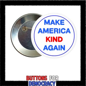 May include: A circular pin-back button with a white background and a thin blue border. The text reads MAKE AMERICA in blue, KIND in red, and AGAIN in blue. The back of the button is metallic silver with a pin mechanism visible on the left side.