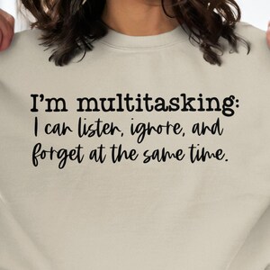 May include: A beige sweatshirt with the text "I'm multitasking: I can listen, ignore, and forget at the same time."