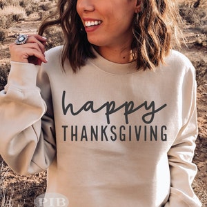 May include: A beige sweatshirt with the text "happy thanksgiving" in black script.