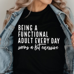Peut inclure: T-shirt noir avec un texte blanc qui dit "Être un adulte fonctionnel tous les jours semble un peu excessif."