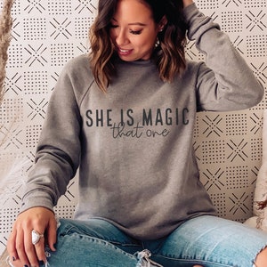 May include: Gray sweatshirt with the text "SHE IS MAGIC that one" printed on the front.