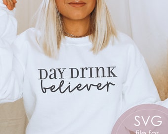 May include: White sweatshirt with the text "Day Drink Believer" in black lettering.  The image also includes a pink circle with the text "SVG file for cutting machines PNG file incl."