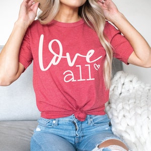 以下が含まれることがあります： 白い「Love all」の文字と小さなハートマークがついた赤いTシャツ
