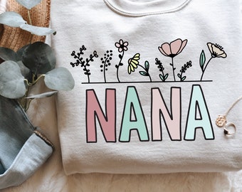 May include: A light grey sweatshirt with a floral design and the word "NANA" in pink, green and light blue.