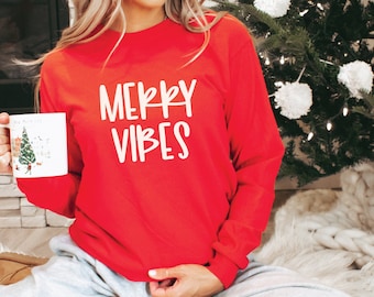 May include: A red long-sleeved sweatshirt with the text "Merry Vibes" in white lettering.