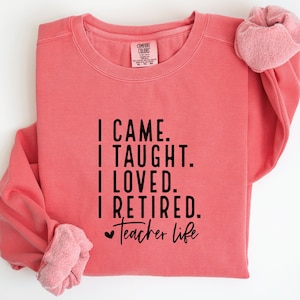 Könnte beinhalten: Ein korallenrosa Sweatshirt mit schwarzem Text, der "I CAME. I TAUGHT. I LOVED. I RETIRED. Teacher life" lautet.