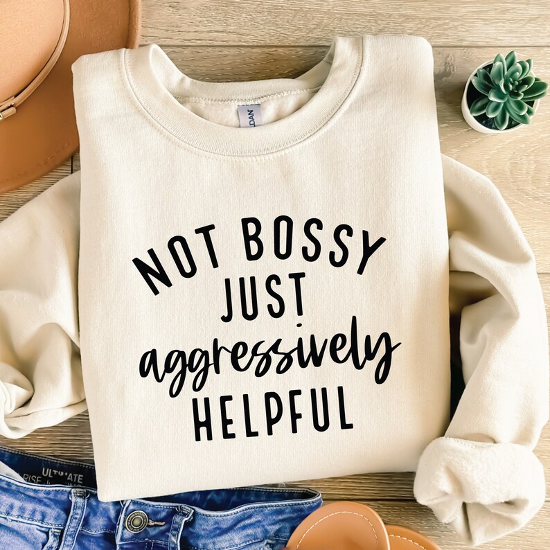 May include: A cream-coloured sweatshirt with the text "Not bossy just aggressively helpful" printed in black.