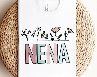 May include: White t-shirt with a colorful floral design and the word "NENA" in pastel colors.