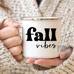 Może przedstawiać: Biały kubek emaliowany z czarnym nadrukiem "fall vibes".