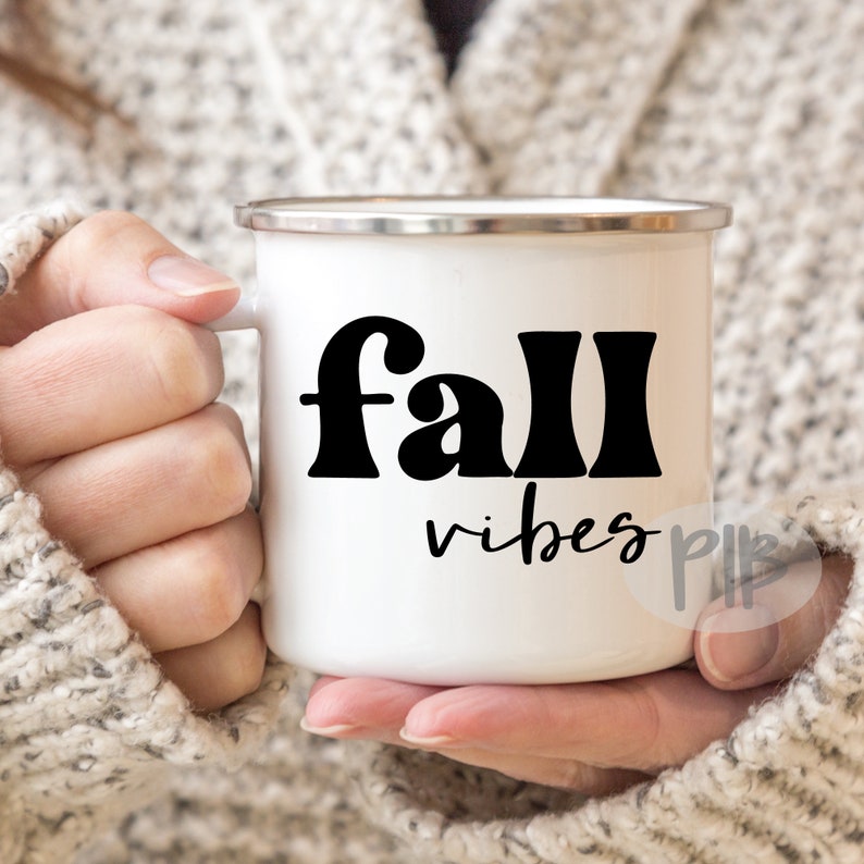 Może przedstawiać: Biały kubek emaliowany z czarnym nadrukiem "fall vibes".