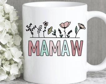 May include: White ceramic coffee mug with a black outline of flowers and the word "MAMAW" in pink, blue, and green.