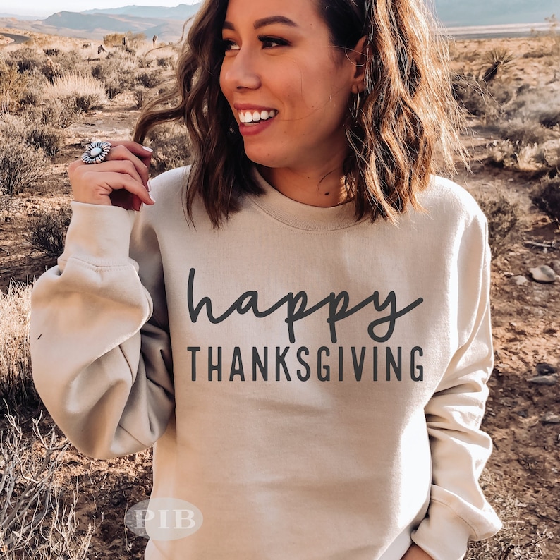 May include: A beige sweatshirt with the text "happy thanksgiving" in black script.