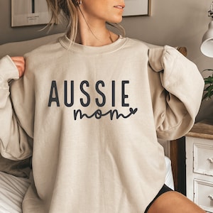 May include: A beige sweatshirt with the text "Aussie mom" in black lettering with a small heart.