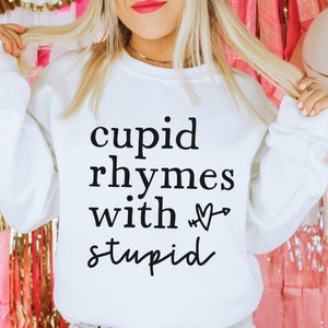 May include: White sweatshirt with black text that reads "cupid rhymes with &hearts; stupid".