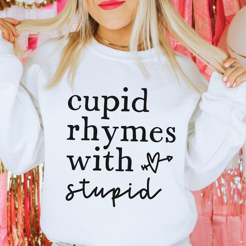 May include: White sweatshirt with black text that reads "cupid rhymes with &hearts; stupid".