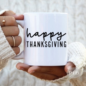 May include: White ceramic mug with black text that reads "happy THANKSGIVING".