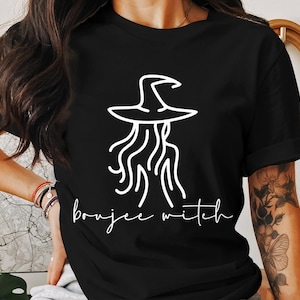 May include: A black t-shirt with a white outline of a witch wearing a hat and the text "boujee witch".