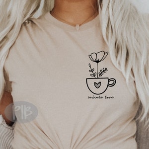 May include: A beige t-shirt with a black line drawing of a flower in a cup with a heart. The text "radiate love" is below the cup.