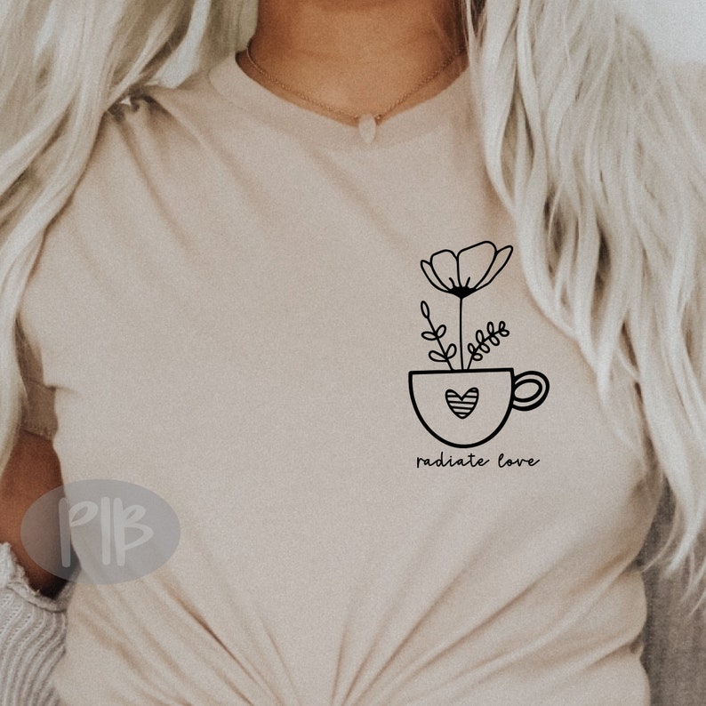 May include: A beige t-shirt with a black line drawing of a flower in a cup with a heart. The text "radiate love" is below the cup.