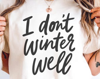 Puede incluir: Camiseta color crema con la frase "I don't Winter Well" en letras negras y en negrita. La camiseta es de estilo casual, adecuada para el uso diario. El texto está centrado en la parte delantera.