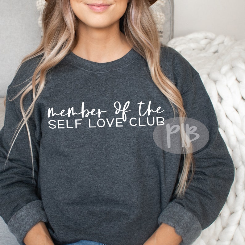 May include: A dark gray sweatshirt with the text "member of the SELF LOVE CLUB" printed in white on the front.