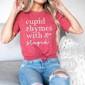May include: Red t-shirt with white text that reads "cupid rhymes with &hearts; stupid".