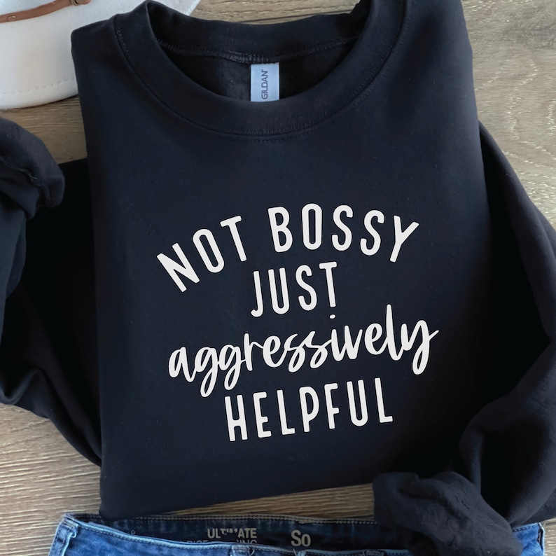 May include: Black sweatshirt with white text that reads "Not bossy just aggressively helpful."