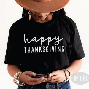 May include: A black t-shirt with the text "happy THANKSGIVING" in white lettering.