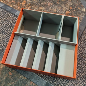 May include: An orange box with a grey foam insert. The insert has multiple compartments for organising small items.