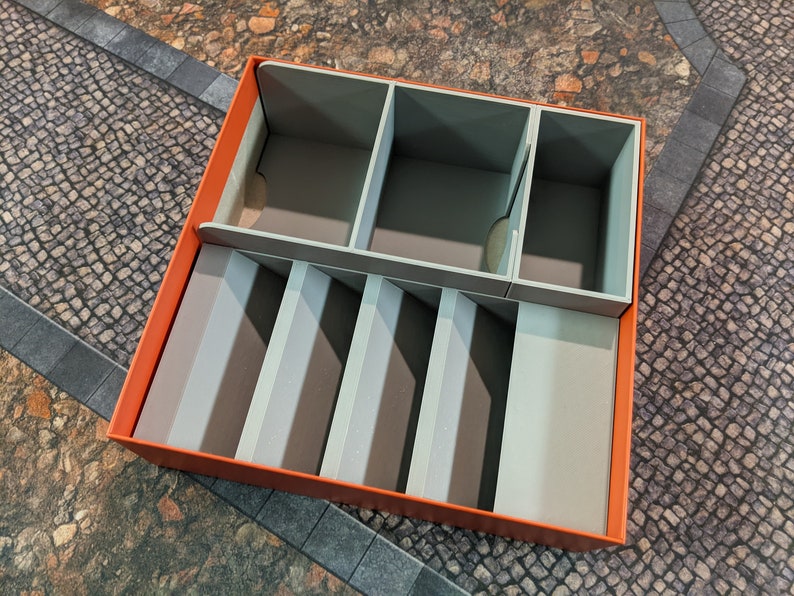 May include: An orange box with a grey foam insert. The insert has multiple compartments for organising small items.