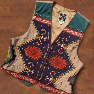 May include: A sleeveless vest featuring a dark purple base with geometric patterns in red, yellow, and white. The garment includes teal panels at the shoulders, silver-toned studs, and a label reading ROPA at the inner neckline. The design incorporates angular shapes and linear accents throughout the front panels.