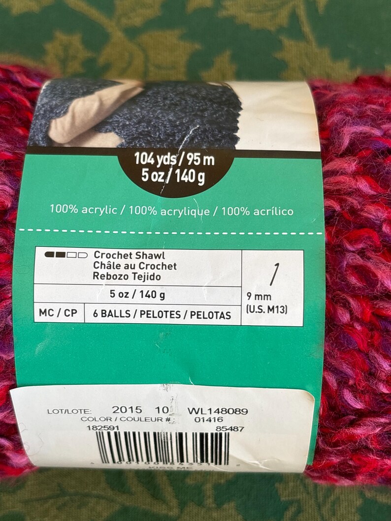K&ouml;nnte beinhalten: Eine Kn&auml;uel pinkfarbenes, violettes und blaues Garn mit einem Etikett, auf dem steht "104 yds/95 m 5 oz/140 g 100% acrylic / 100% acrylique / 100% acr&iacute;lico Crochet Shawl Ch&acirc;le au Crochet Rebozo Tejido 5 oz/ 140 g 6 BALLS/PELOTES / PELOTAS 1 9 mm (U.S. M13) LOT/LOTE: 2015 10 COLOR/COULEUR # 182591 WL148089 01416 85487"