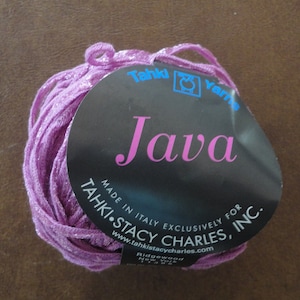 May include: A skein of purple yarn with a label that reads "Tahki Yarns Java Made in Italy Exclusively for Tahki Stacy Charles, Inc. www.tahkistacycharles.com Ridgewood, New York 11385"