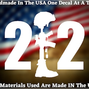 May include: White vinyl decal with the number 22 and a silhouette of a fallen soldier with a rifle, helmet, and boots. The background is a blurred image of the American flag. The text "Handmade In The USA One Decal At A Time" is at the top of the image. The text "All Materials Used Are Made IN The USA" is at the bottom of the image.
