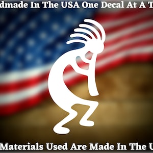 May include: White vinyl decal of a stylized Kokopelli figure, a traditional Native American symbol, against a blurred background of the American flag. The decal is handmade in the USA.