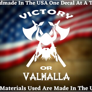 May include: White vinyl decal featuring a Viking helmet and crossed axes. The text "VICTORY OR VALHALLA" is displayed below the image. The decal is set against a blurred American flag background.