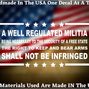 May include: A white decal with the text "A well regulated militia, being necessary to the security of a free state, the right to keep and bear arms, shall not be infringed." The decal is on a blurred background of the American flag.