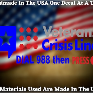 May include: A blue and red decal with a star and dots, with the text "Veterans Crisis Line" in gray and blue text. The text "DIAL 988 then PRESS 1" is in blue and red text. The decal is on a blurred background of an American flag.
