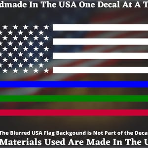 May include: A decal depicting the American flag with blue, green, and red stripes. The text at the top says "Handmade In The USA One Decal At A Time." The text at the bottom says "The Blurred USA Flag Background is Not Part of the Decal All Materials Used Are Made In The USA."